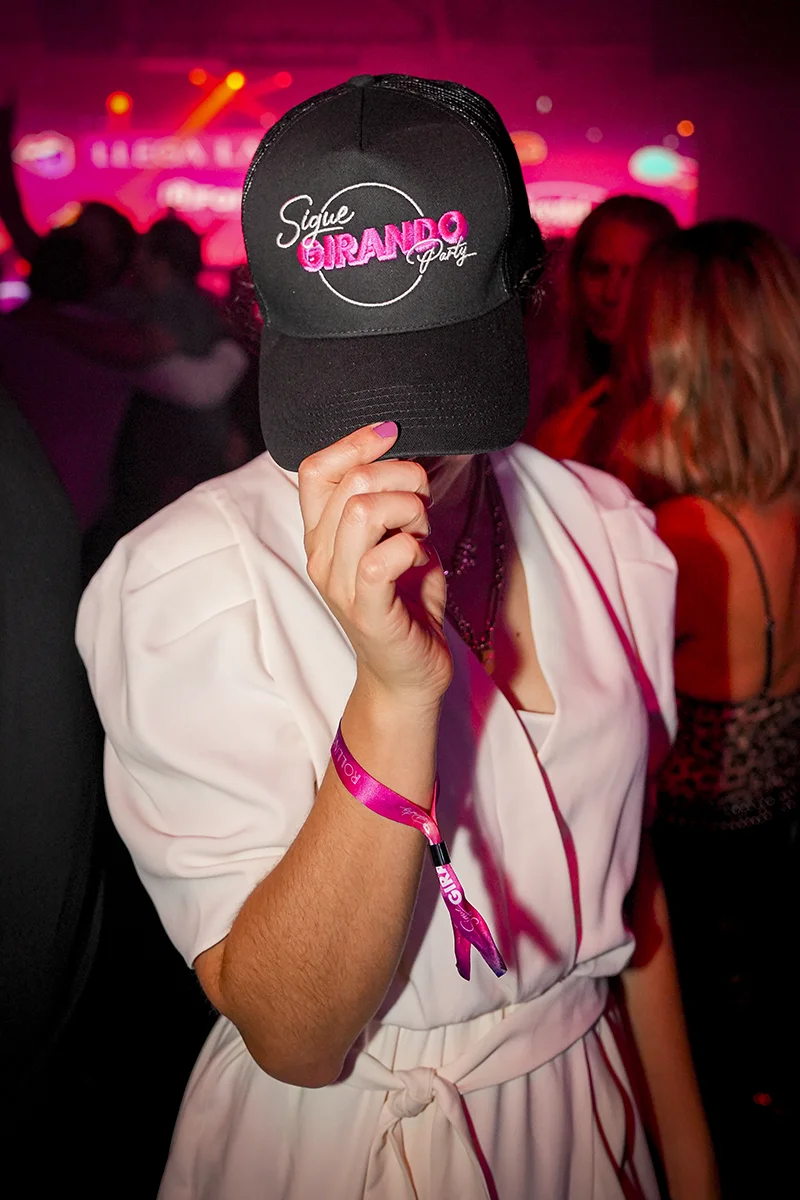 Mujer en la fiesta luciendo una gorra negra con el logo de Sigue Girando Party